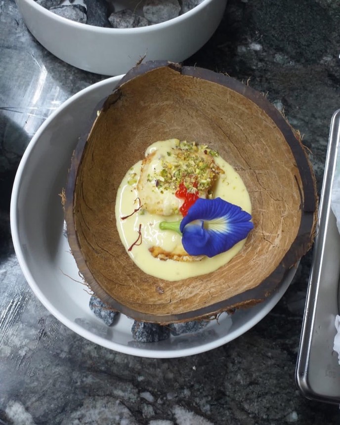 Saffron and pistachio dessert served in a coconut shell